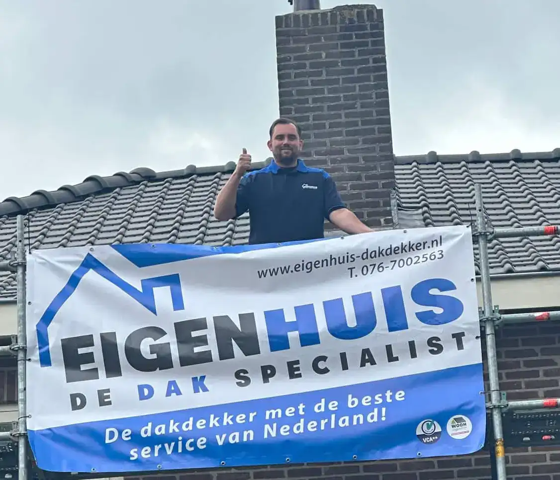 Dakdekker poseert met duim omhoog achter EigenHuis De Dak Specialist-banner op dak