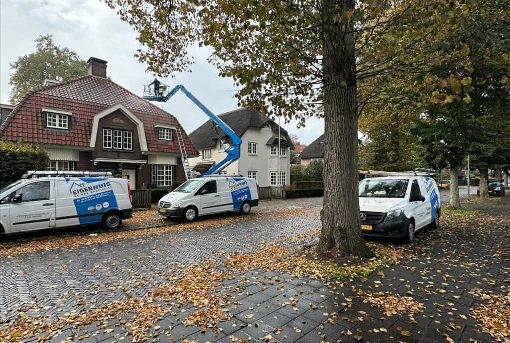 Hoogwerker en Eigenhuis-bussen bij woninginspectie van klassiek huis in herfst