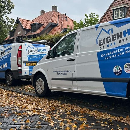 Twee bedrijfswagens van Eigenhuis De Dak Specialist geparkeerd voor woonhuis in herfst