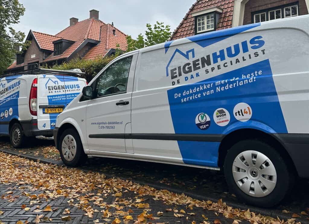Twee bedrijfswagens van Eigenhuis De Dak Specialist geparkeerd voor woonhuis in herfst