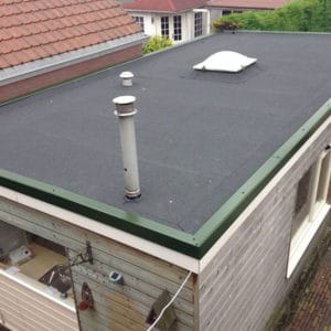 Plat dak van aanbouw met zwarte bitumenbedekking, dakdoorvoer en lichtkoepel